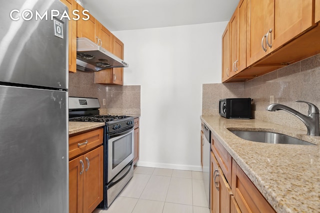 kitchen with light tile patterned floors, a sink, stainless steel appliances, under cabinet range hood, and backsplash