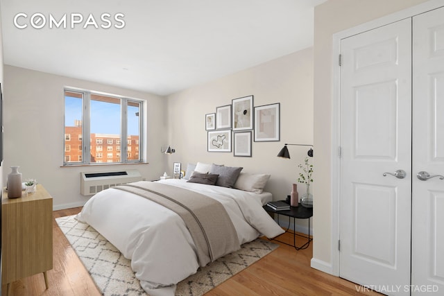 bedroom featuring heating unit, baseboards, and wood finished floors