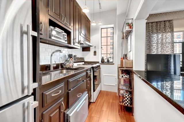 kitchen with a warming drawer, white gas stove, a sink, backsplash, and freestanding refrigerator