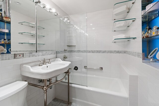 bathroom with toilet, tile walls, and tiled shower / bath