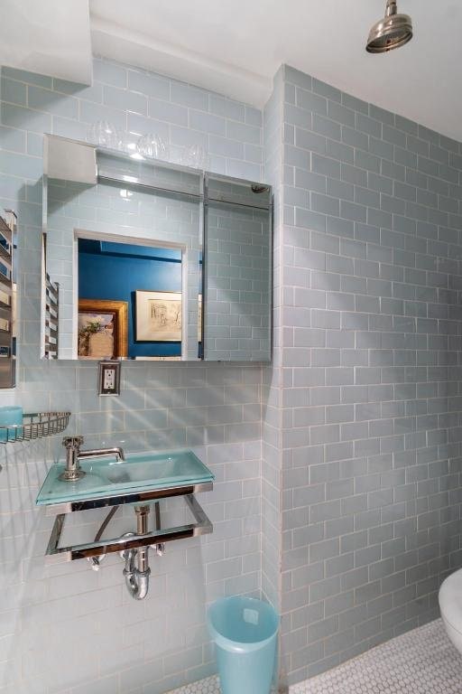 bathroom featuring decorative backsplash, sink, and tile walls