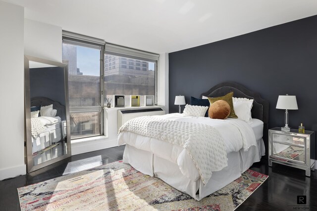 bedroom featuring a wall of windows, dark hardwood / wood-style flooring, and multiple windows