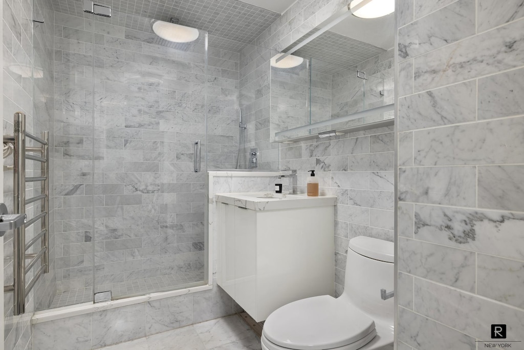 bathroom featuring a stall shower, marble finish floor, vanity, and toilet