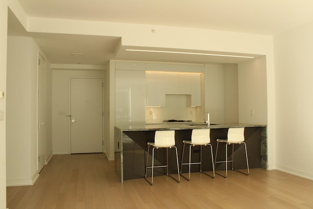 bar with baseboards, a sink, and light wood-style floors