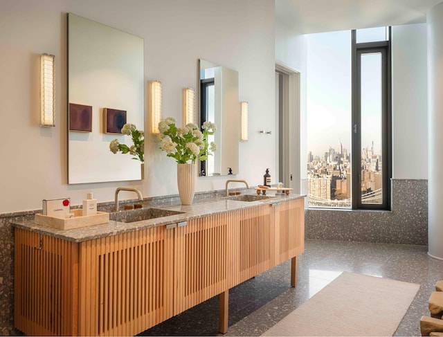 full bathroom featuring double vanity, granite finish floor, and a sink