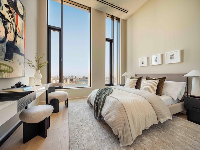 bedroom with expansive windows, a high ceiling, and wood finished floors