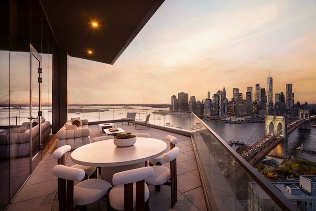 patio terrace at dusk featuring a balcony and a water view