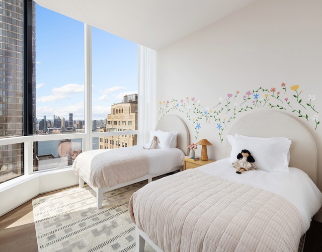 bedroom with a city view and wood finished floors