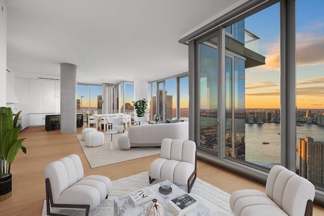 living room with expansive windows, a water view, and light wood-type flooring