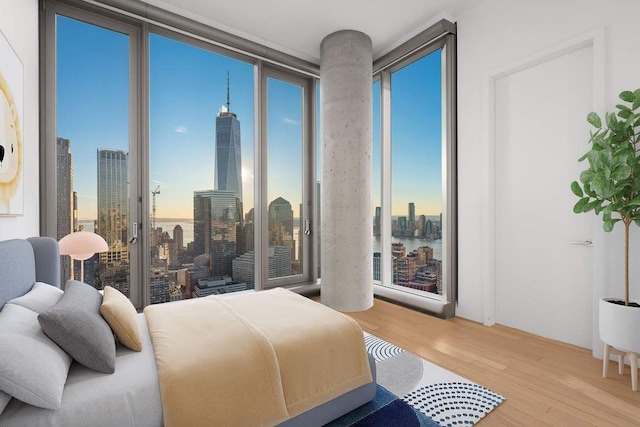 bedroom with a wall of windows and light hardwood / wood-style floors