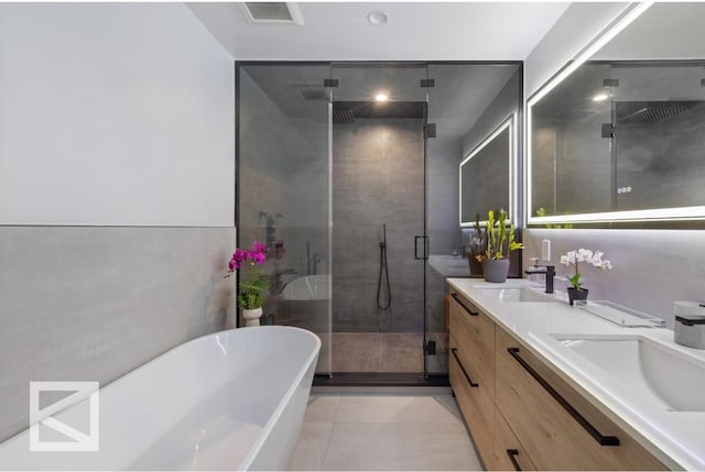 full bath with double vanity, visible vents, a freestanding tub, a shower stall, and a sink