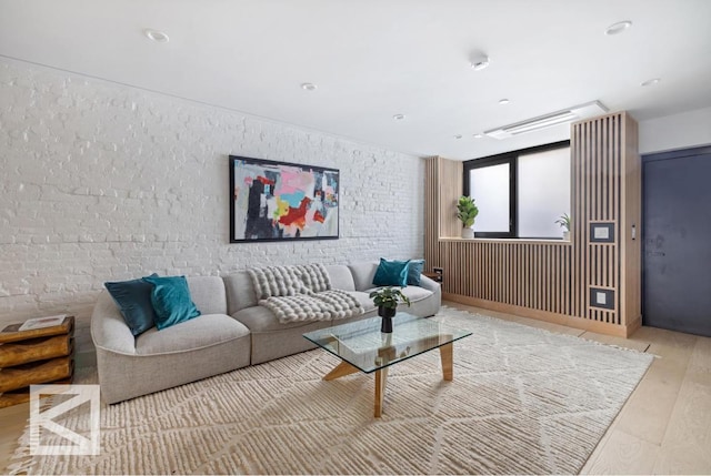 living area with brick wall and wood finished floors