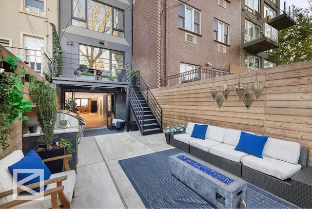 view of patio / terrace with stairs, fence, and an outdoor living space with a fire pit