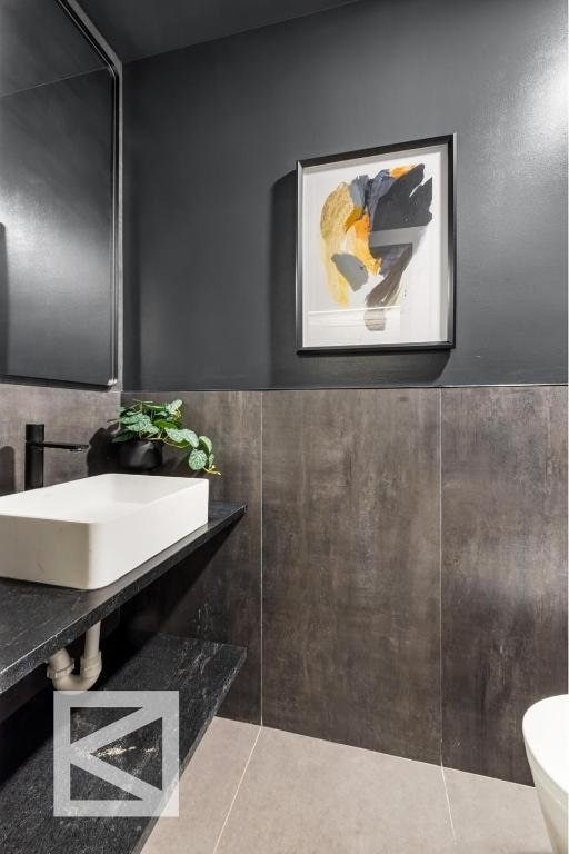 bathroom with tile patterned flooring, a wainscoted wall, a sink, and toilet