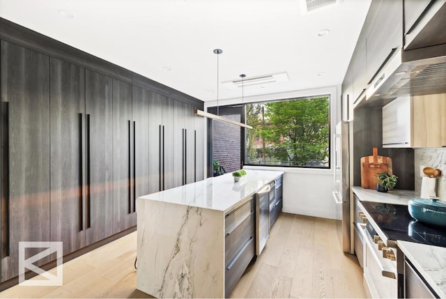 kitchen featuring light wood finished floors, light stone countertops, hanging light fixtures, a kitchen island, and modern cabinets