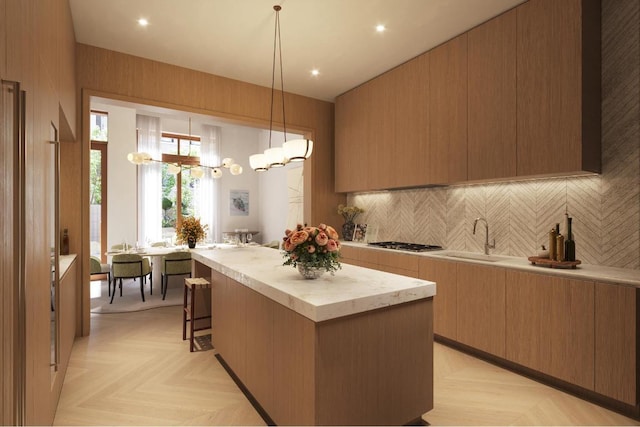 kitchen with a kitchen island, decorative light fixtures, stainless steel gas stovetop, decorative backsplash, and light parquet floors