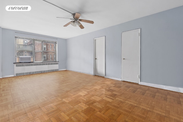 spare room with ceiling fan, radiator heating unit, and light parquet floors