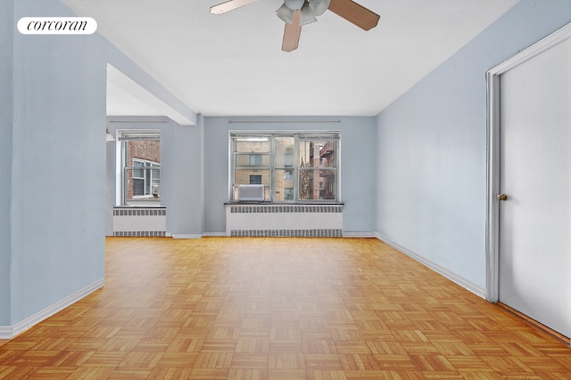 unfurnished room with light parquet floors, ceiling fan, and radiator heating unit