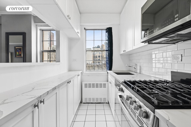 kitchen with tasteful backsplash, radiator heating unit, appliances with stainless steel finishes, a sink, and a wealth of natural light