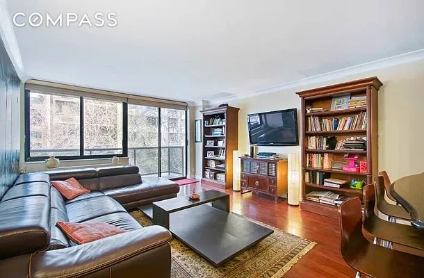 living room with a wall of windows, wood finished floors, and crown molding