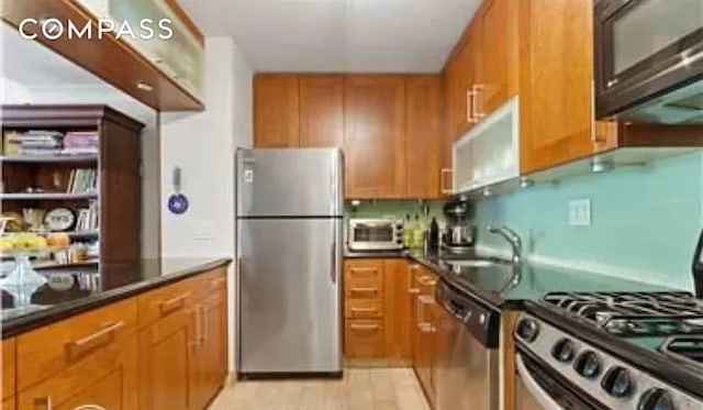 kitchen featuring a sink, stainless steel appliances, brown cabinets, and dark countertops