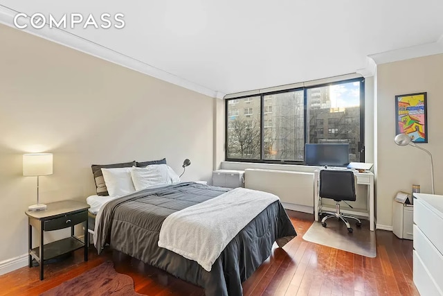 bedroom with baseboards, wood-type flooring, and ornamental molding