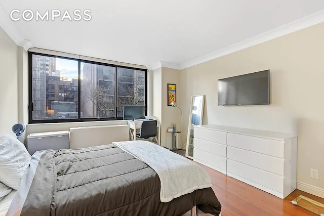 bedroom featuring crown molding, wood finished floors, and baseboards