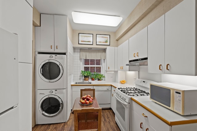 kitchen with white appliances, dark wood-type flooring, under cabinet range hood, light countertops, and stacked washing maching and dryer