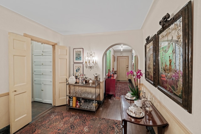 corridor with arched walkways and wood finished floors