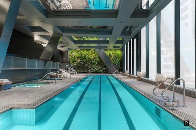 indoor community pool featuring an in-ground hot tub and a patio area