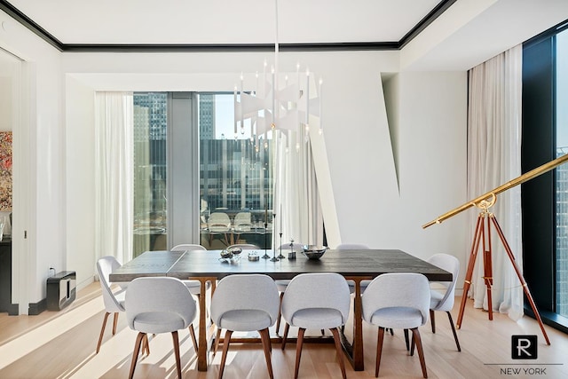 dining room featuring light wood finished floors, ornamental molding, and baseboards