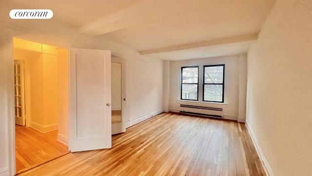 319 E 50th St Unit 5G, New York City, NY 10022 - unfurnished bedroom with light wood-style floors, a baseboard radiator, and beamed ceiling
