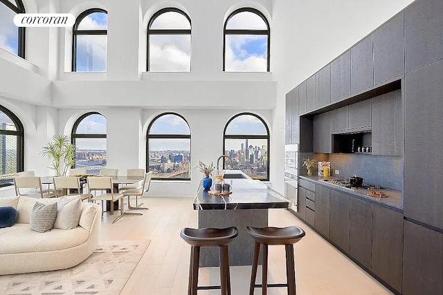 kitchen with tasteful backsplash, light wood finished floors, a kitchen bar, stainless steel gas stovetop, and a sink