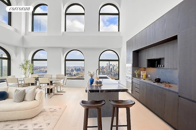130 William St Unit 46A, New York City, NY 10038 - kitchen featuring stainless steel gas cooktop, a breakfast bar area, a towering ceiling, modern cabinets, and decorative backsplash