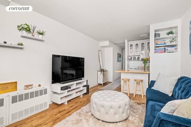 living room featuring built in shelves, radiator, and hardwood / wood-style floors