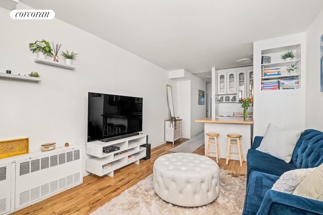 living area with visible vents, radiator heating unit, and wood finished floors