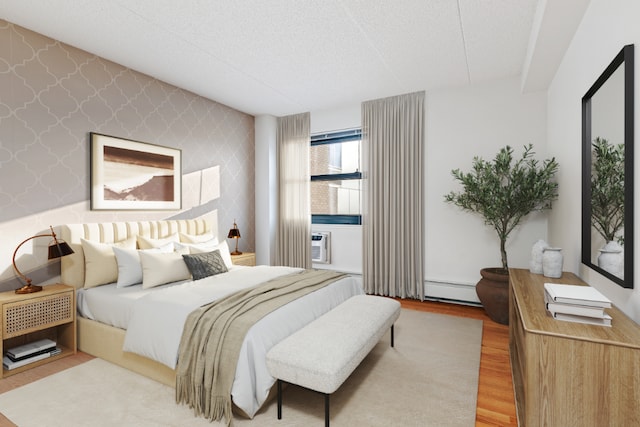 bedroom with wallpapered walls, a baseboard radiator, an accent wall, wood finished floors, and a textured ceiling