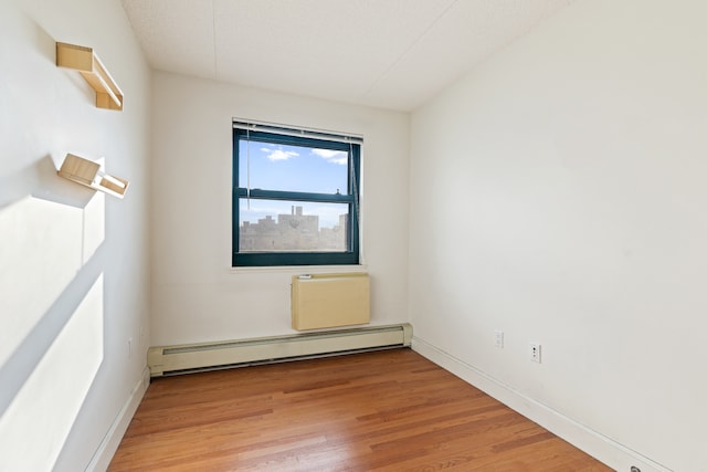 unfurnished room featuring light wood-style floors, baseboards, and baseboard heating