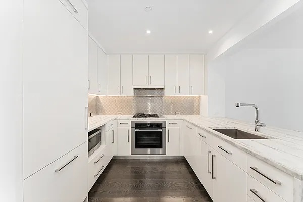 kitchen featuring white cabinetry, appliances with stainless steel finishes, tasteful backsplash, light stone counters, and sink