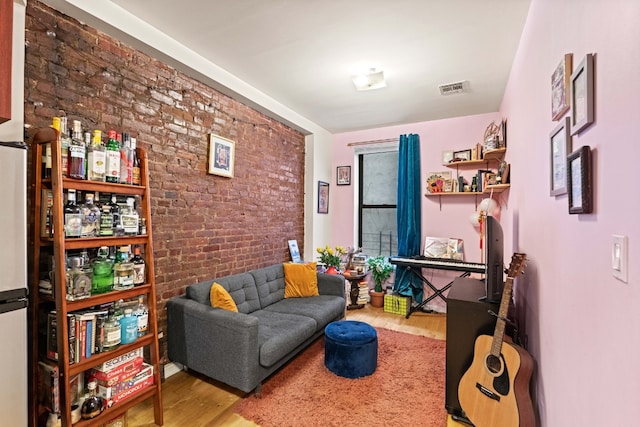 living room with wood-type flooring and brick wall