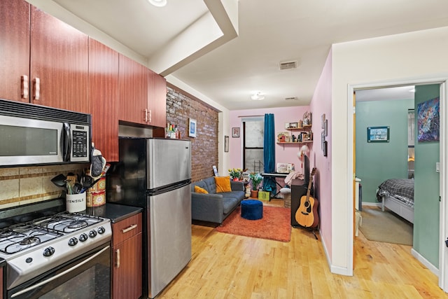 kitchen featuring light wood finished floors, visible vents, decorative backsplash, dark countertops, and stainless steel appliances