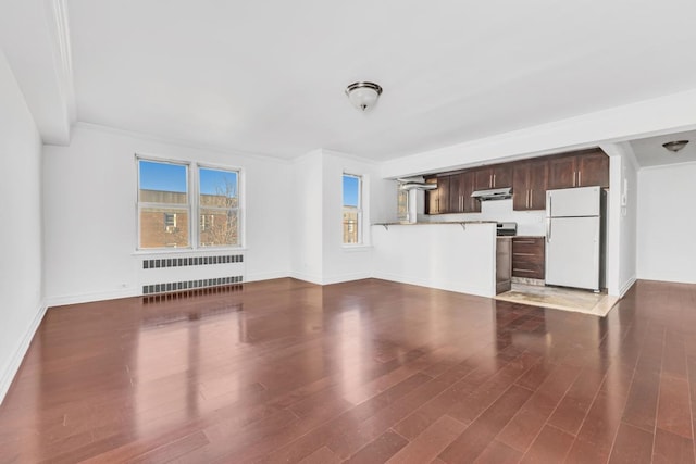 unfurnished living room featuring dark wood-type flooring, a wealth of natural light, radiator heating unit, and ornamental molding