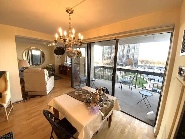 dining space featuring light wood-style floors, a chandelier, and a city view