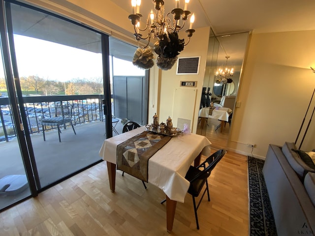 dining space with a chandelier, baseboards, visible vents, and light wood-style flooring