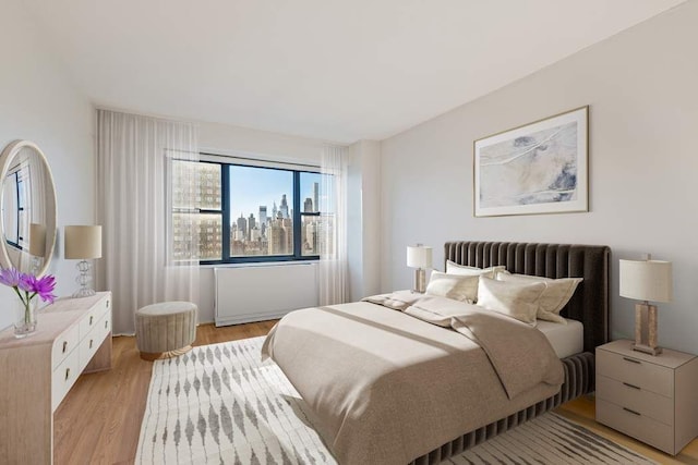 bedroom with light wood-style flooring and a view of city