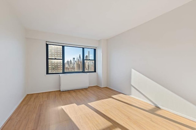 unfurnished bedroom with radiator heating unit and light wood-type flooring