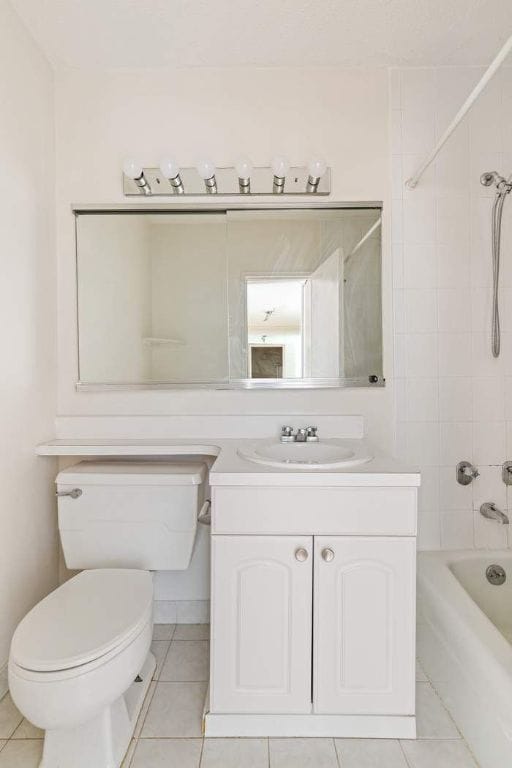 full bathroom with tile patterned floors, vanity, toilet, and tiled shower / bath combo