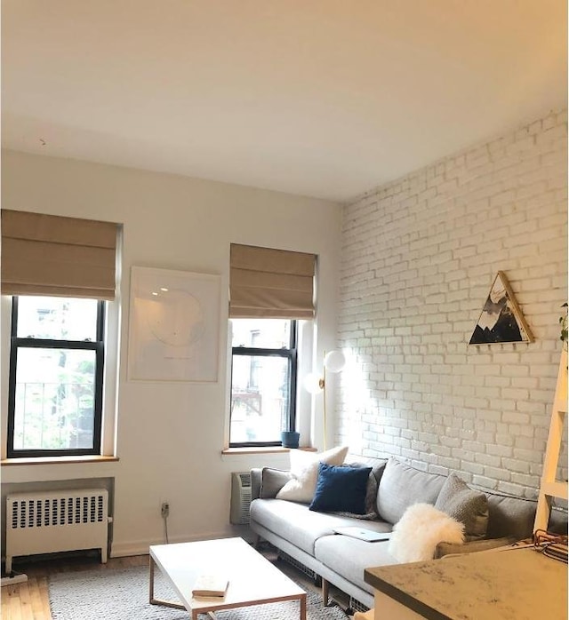 living room with radiator, brick wall, and wood finished floors