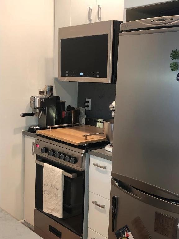 kitchen featuring stainless steel appliances, dark countertops, and white cabinetry