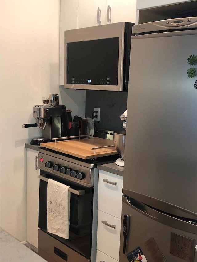 kitchen featuring dark countertops, appliances with stainless steel finishes, and white cabinets